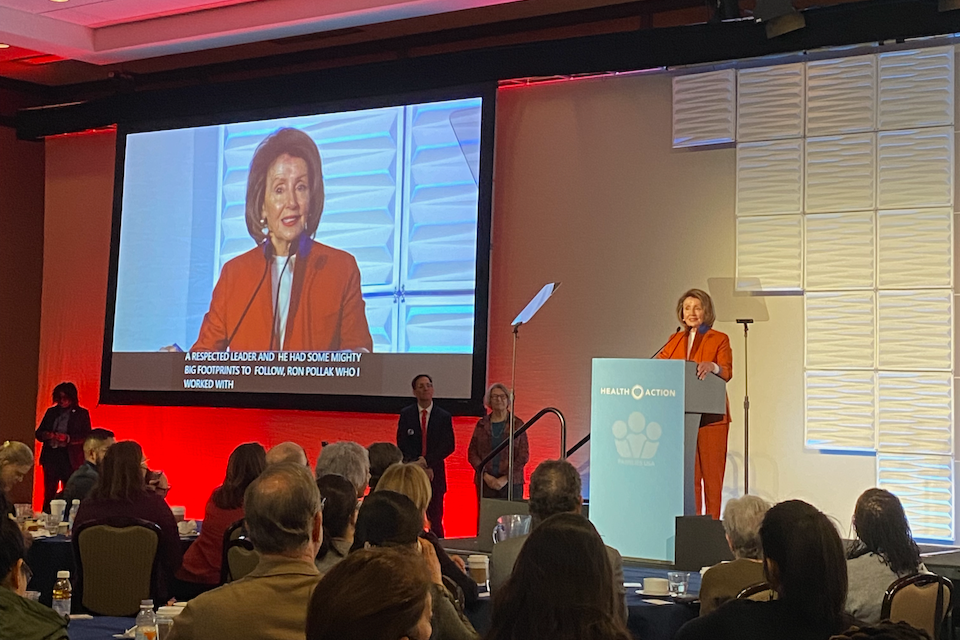 Nancy Pelosi speaking on stage at a conference